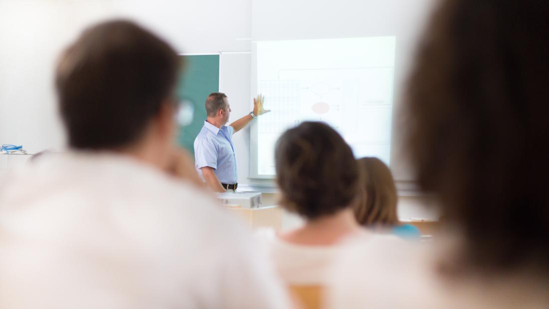 A lecturer pointing to a whiteboard