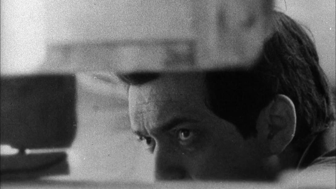 a black and white imnage of Stanley Kibrick peering through set