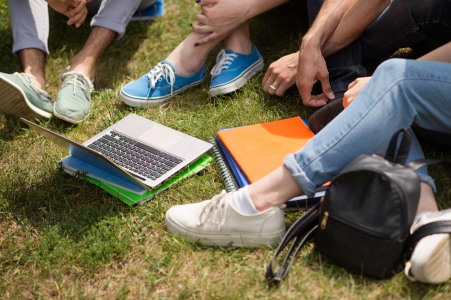 Student sitting on grass looking at laptop