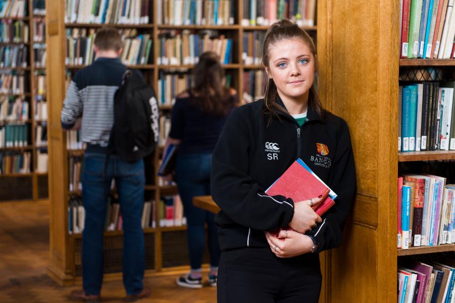 A student carrying books in the Shankland Library