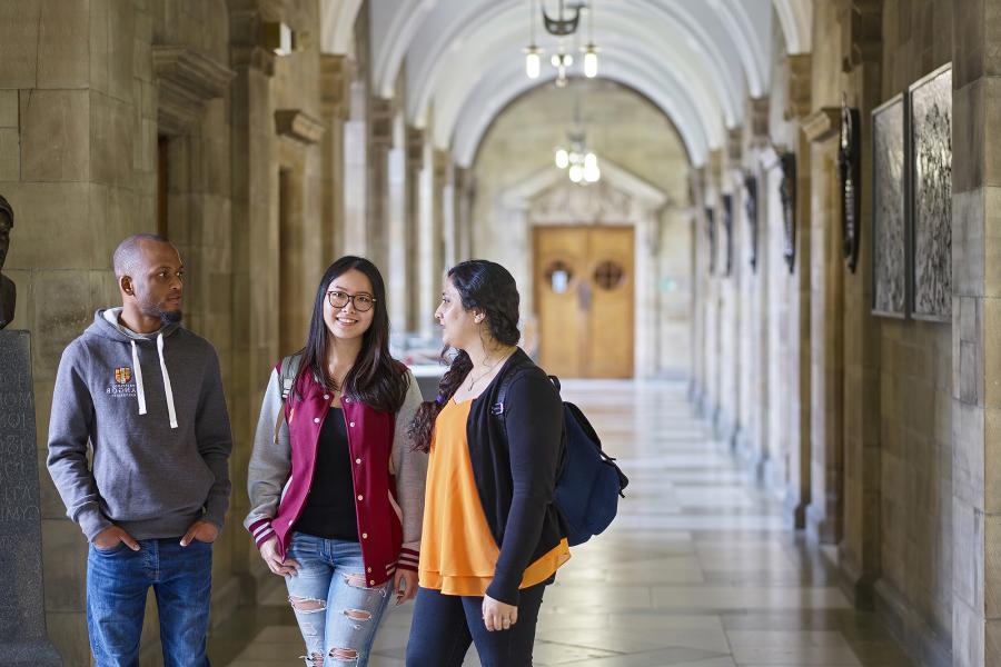 three students chatting in the corridor at the historic Main Arts building 