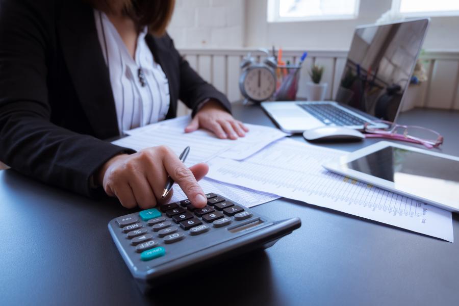 professional working on finances at a desk with a calculator and laptop