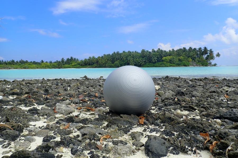 A sports ball lies on the beach on a tropical island