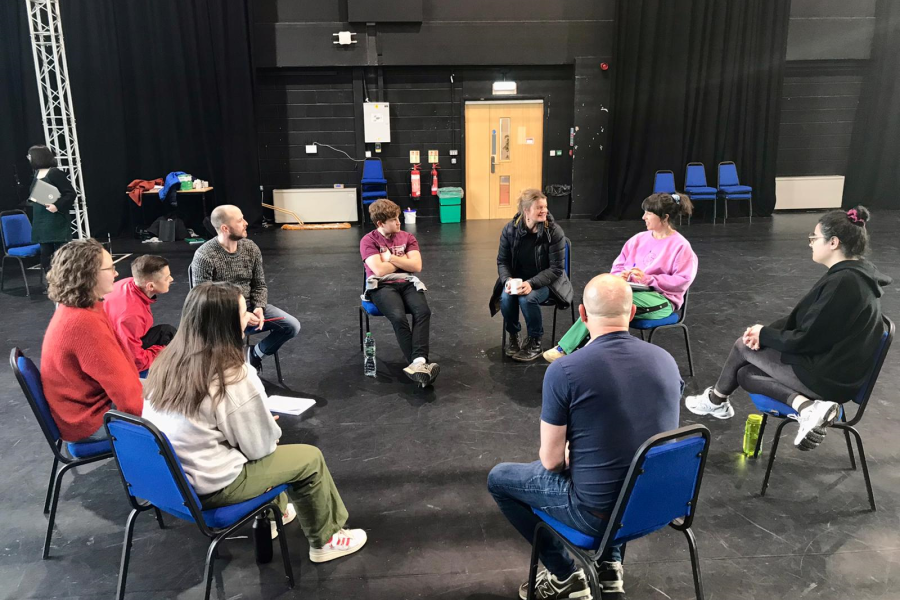 aa group of people in a circle rehearsing a play