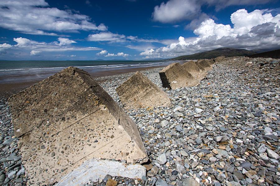 Anti tank concrete blocks among pebbles on a beach