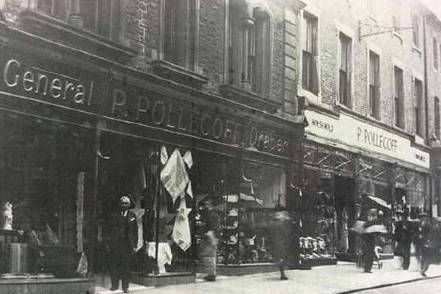 A historic black and white picture taken of the previous Pollecoff Department store on Bangor High Street with what is presumably, Mr Pollecoff standing outside the front door 