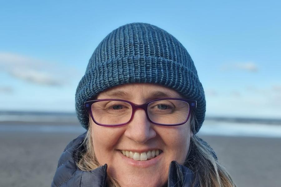 Karen Tuson on a beach with a blue hat on 