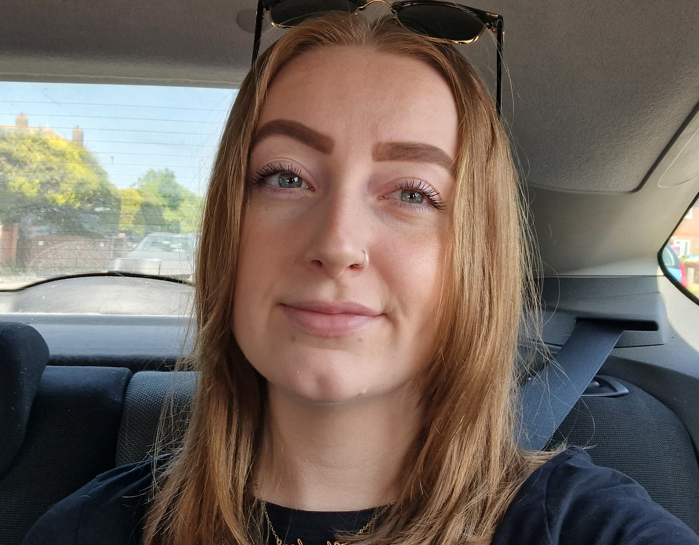 Charley Woollams in a car, with sunglasses on her head