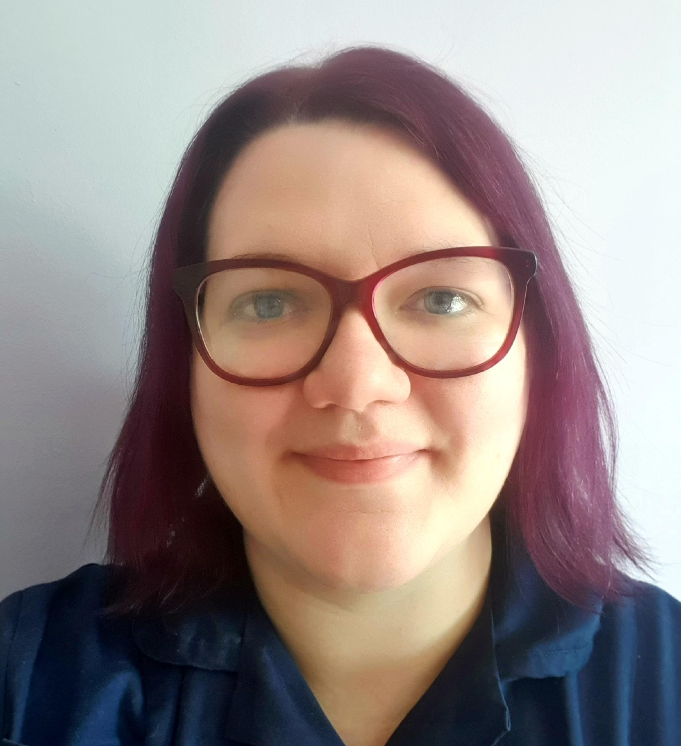 Kayleigh Demain wearing red glasses looking directly at camera. 