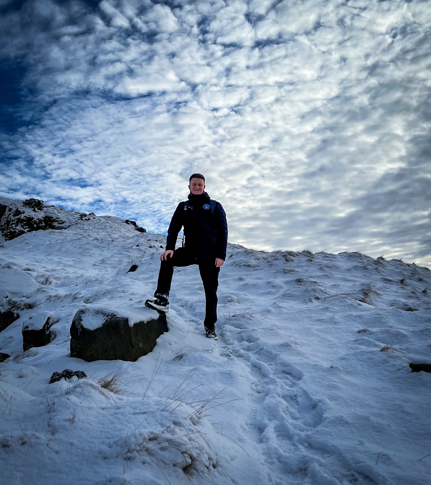 Joseph Varga yn sefyll ar fynydd mewn eira