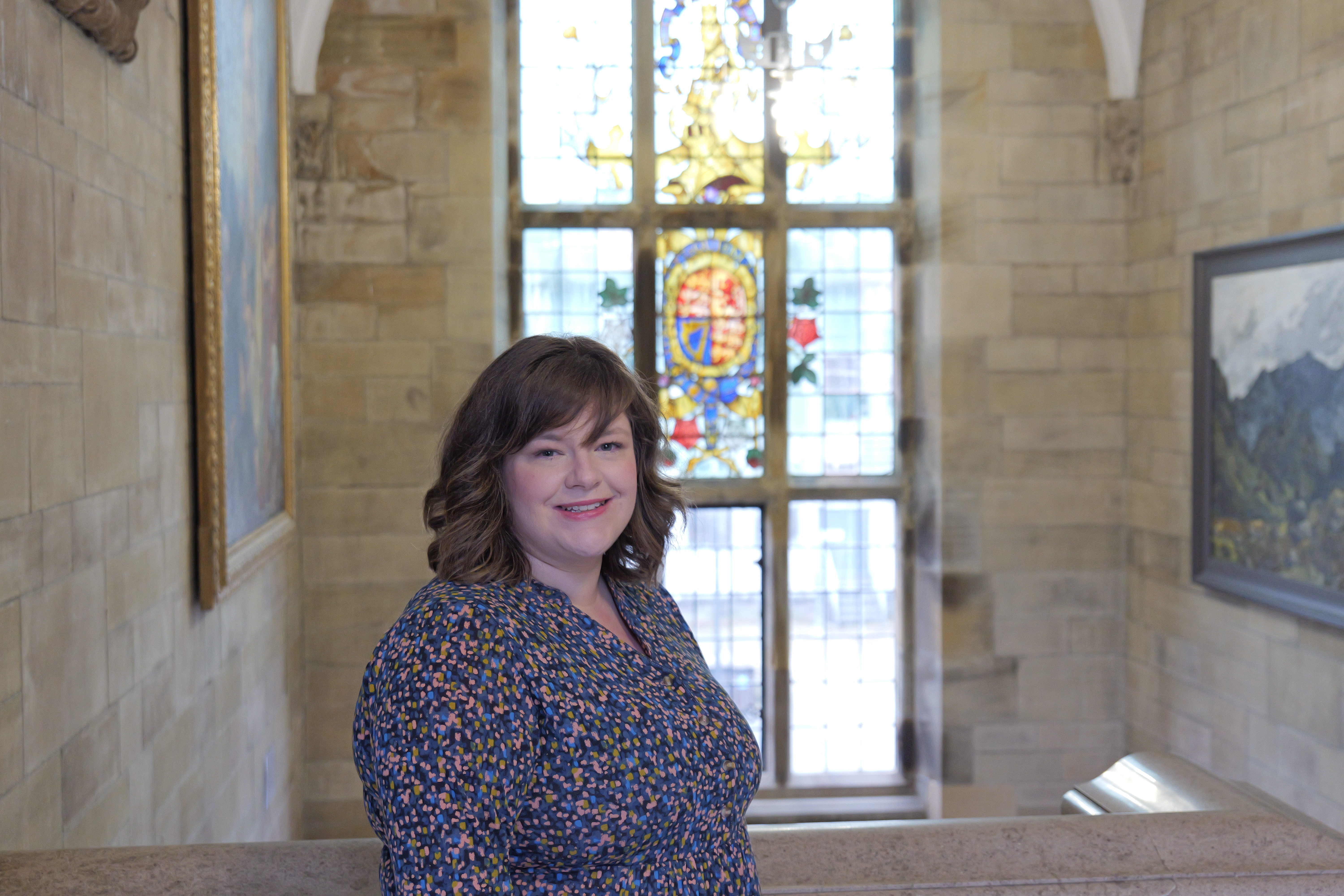 Image of Sarah Cooper in front of a stained glass window of Bangor University 