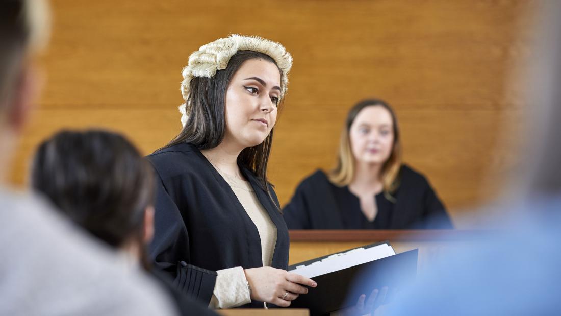 A student wearing a robe and wig in a moot court