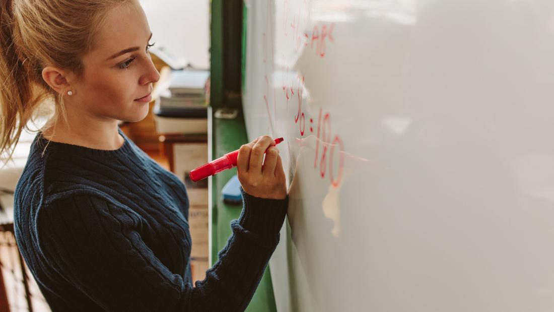 Teacher writing on a white board in the classroom