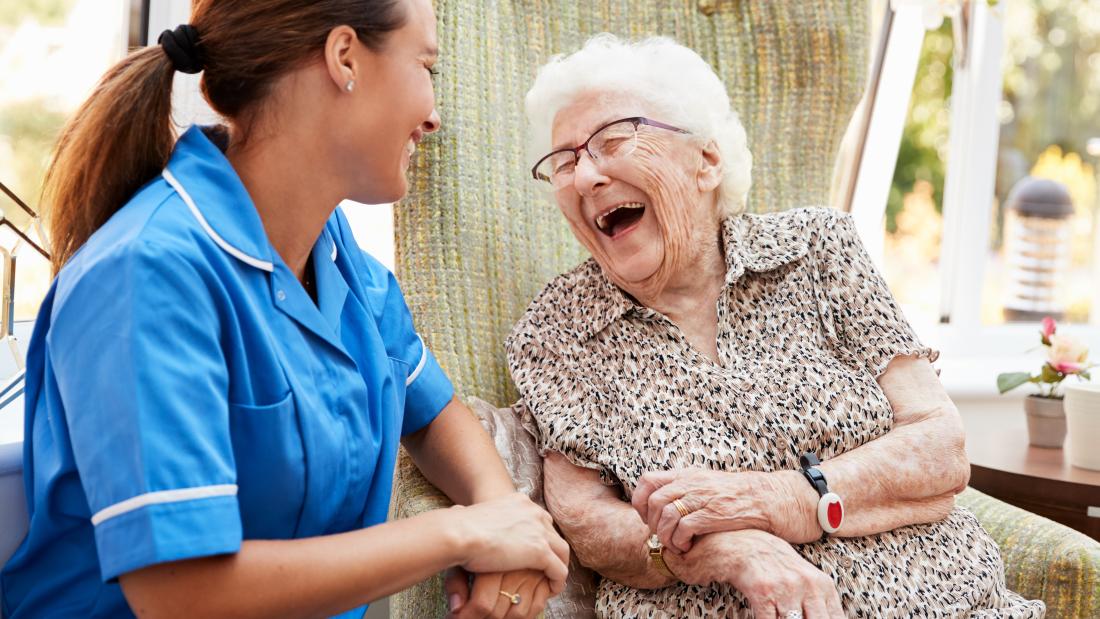 Woman sitting in a chair and talking to a nurse in a nursing home