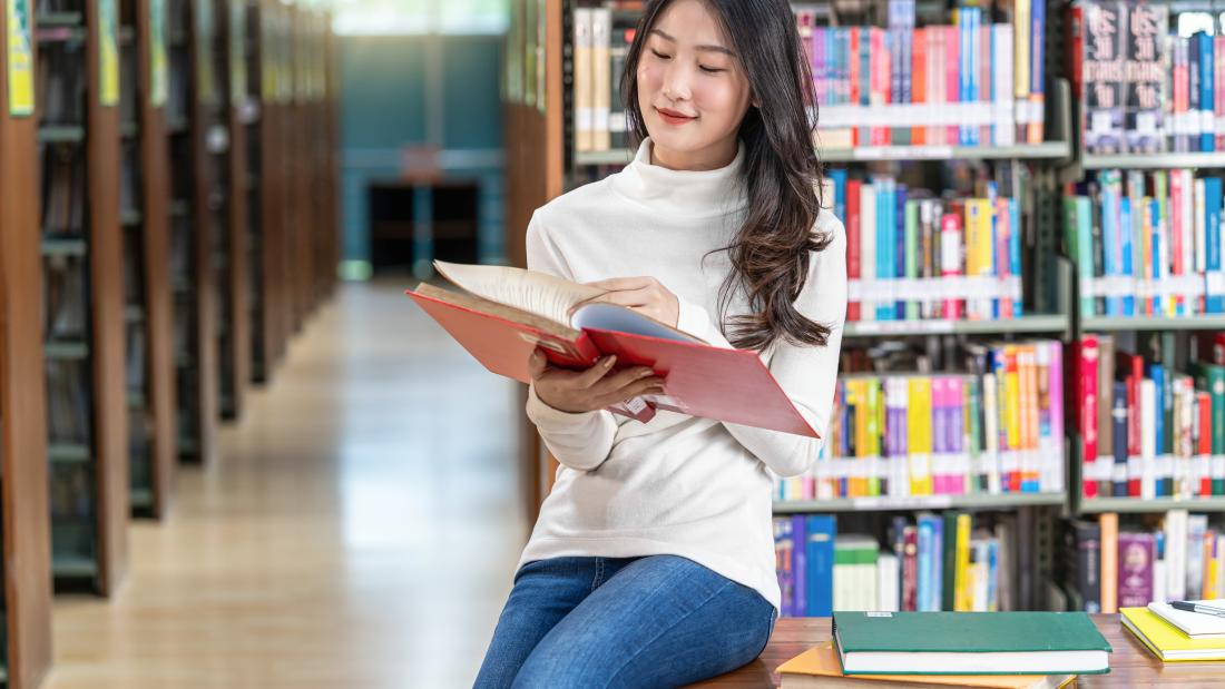 Student reading a book in the library 