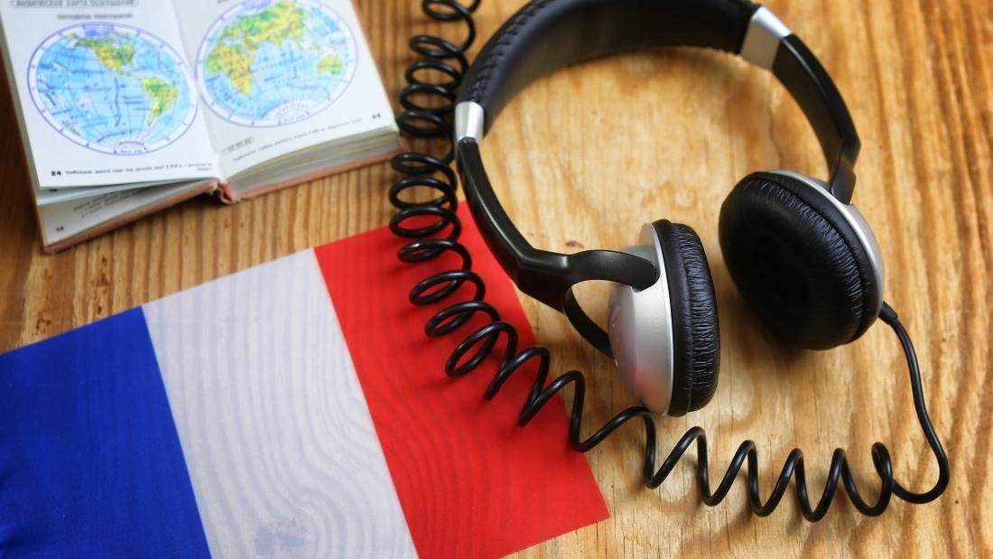 Headphones and book on a desk with a French flag