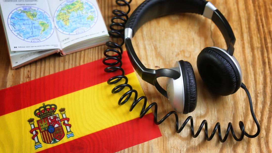 Headphones and book with a Spanish flag on a desk.