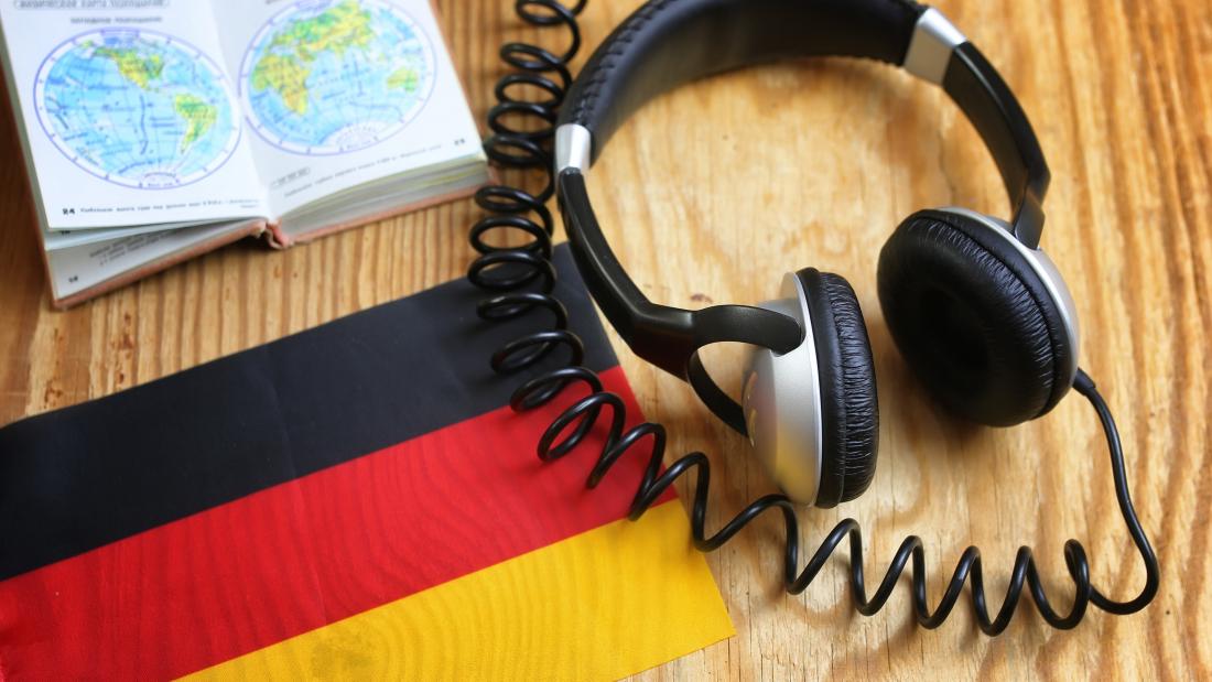 Headphones and book on a desk with a German flag