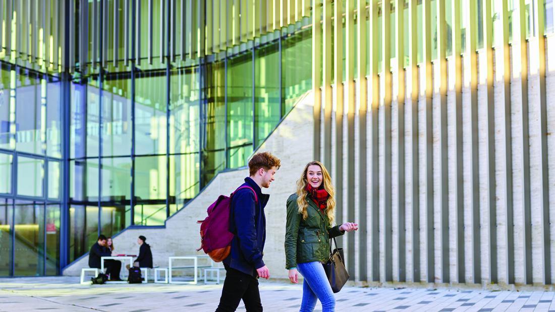 Two students chatting walking outside the Pontio building 