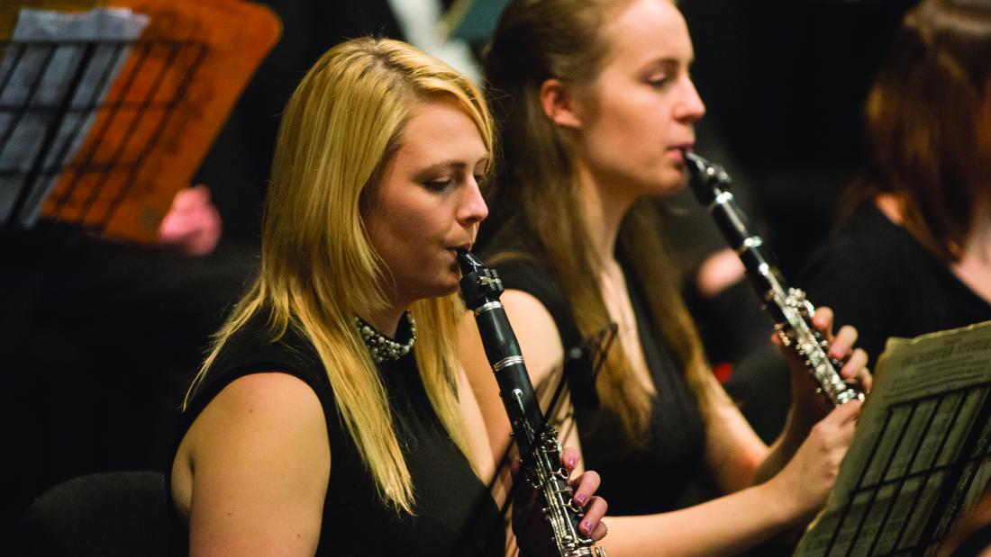 Two students playing clarinet in an orchestra