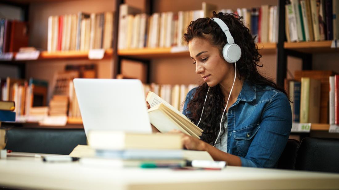 Student listening to headphones while studying in the library