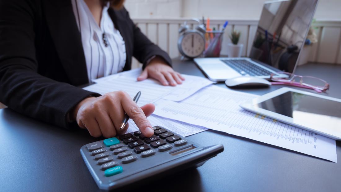 professional working on finances at a desk with a calculator and laptop