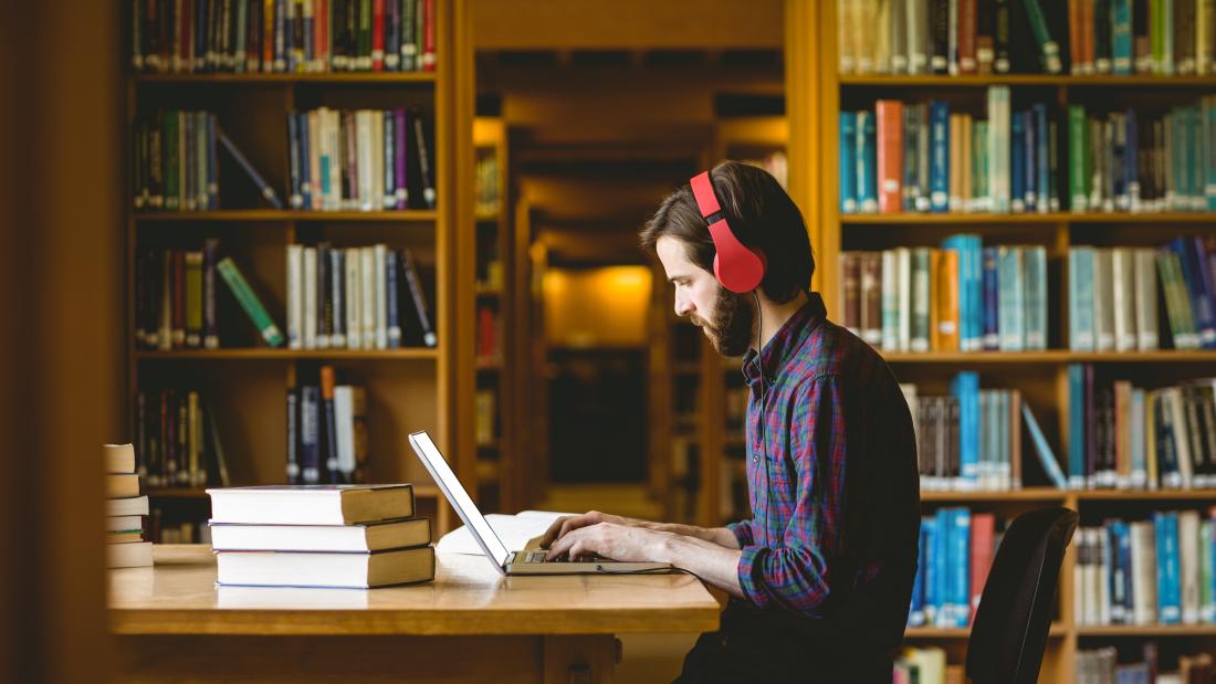 Student studying in the library wearing headphones