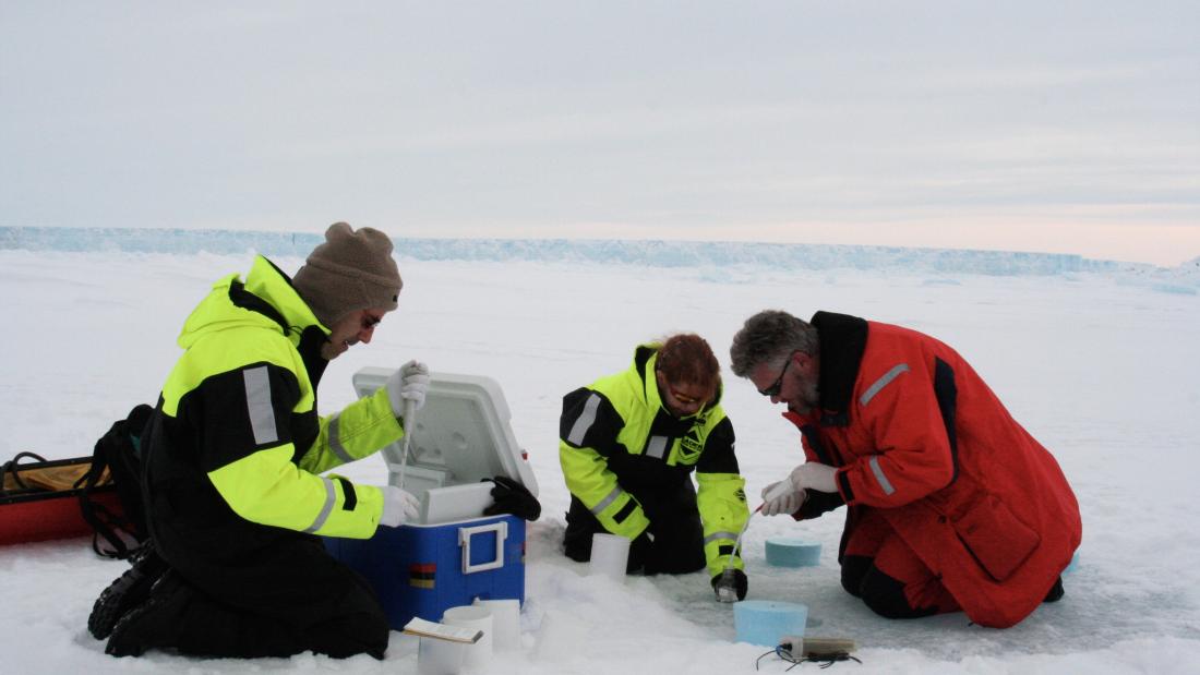 people chrouched at work on antarctic sea ice.