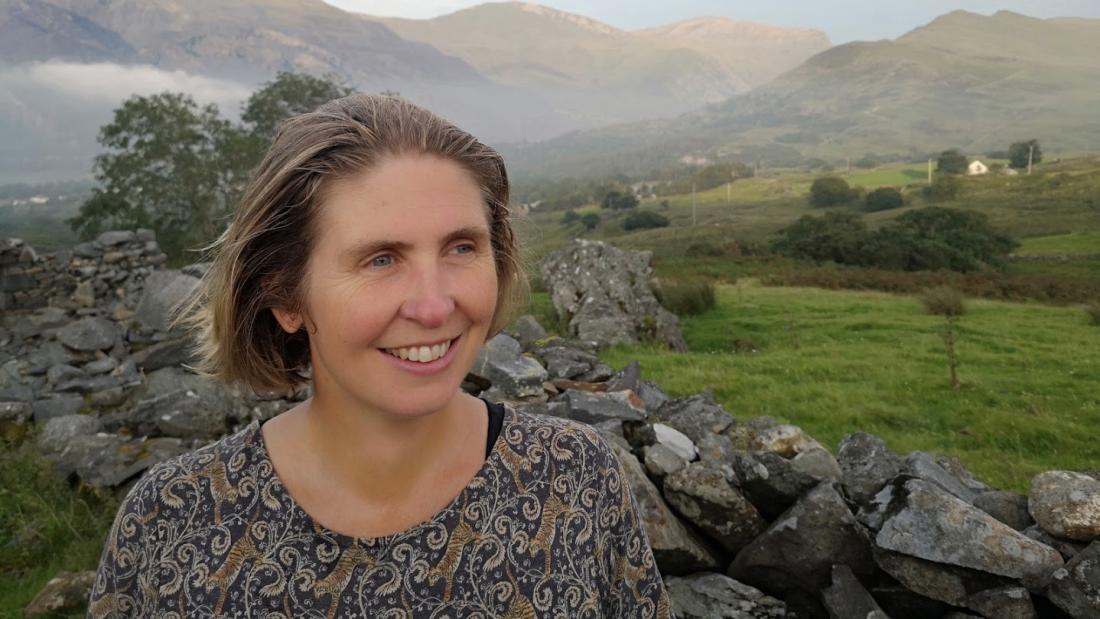 Woman looks to the right with mountain backdrop