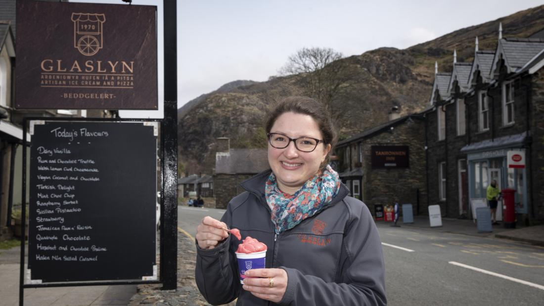 Young woman eats ice cream outside Glaslyn Ices, Bbeddgelert