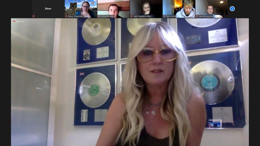 Jules Peters has long blond hair and spectacles and is speaking to camera, above is a row of small images of other participants in the call.