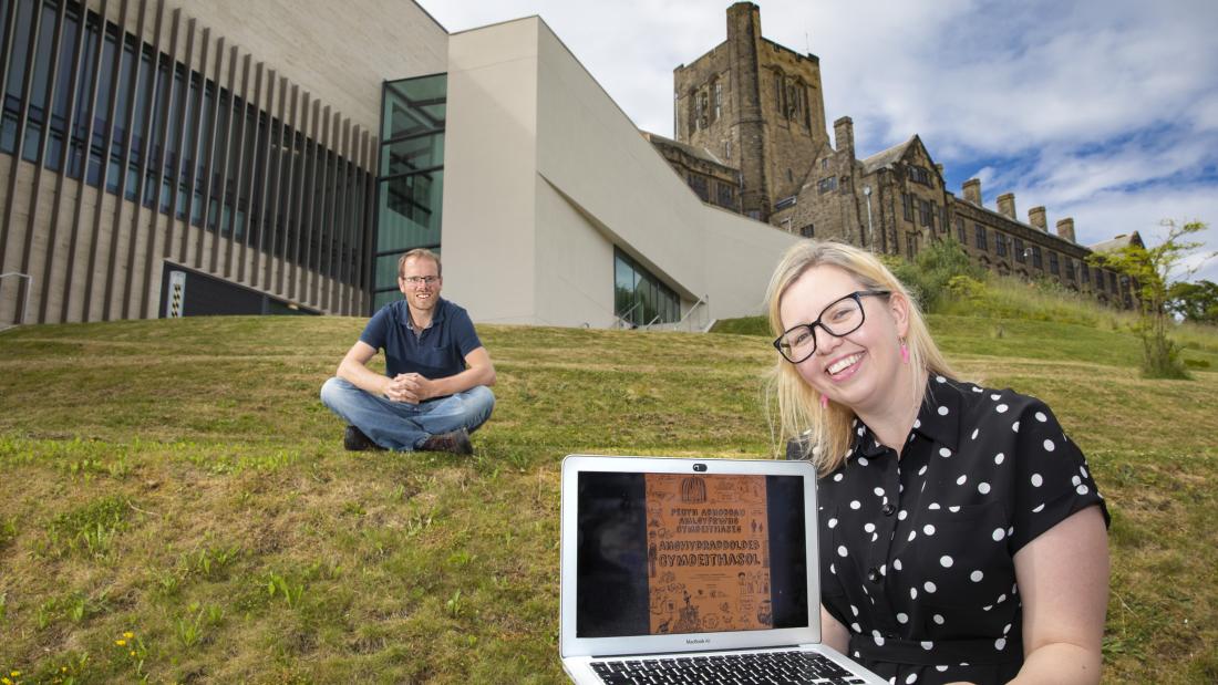 Person holding a laptop with university in the background