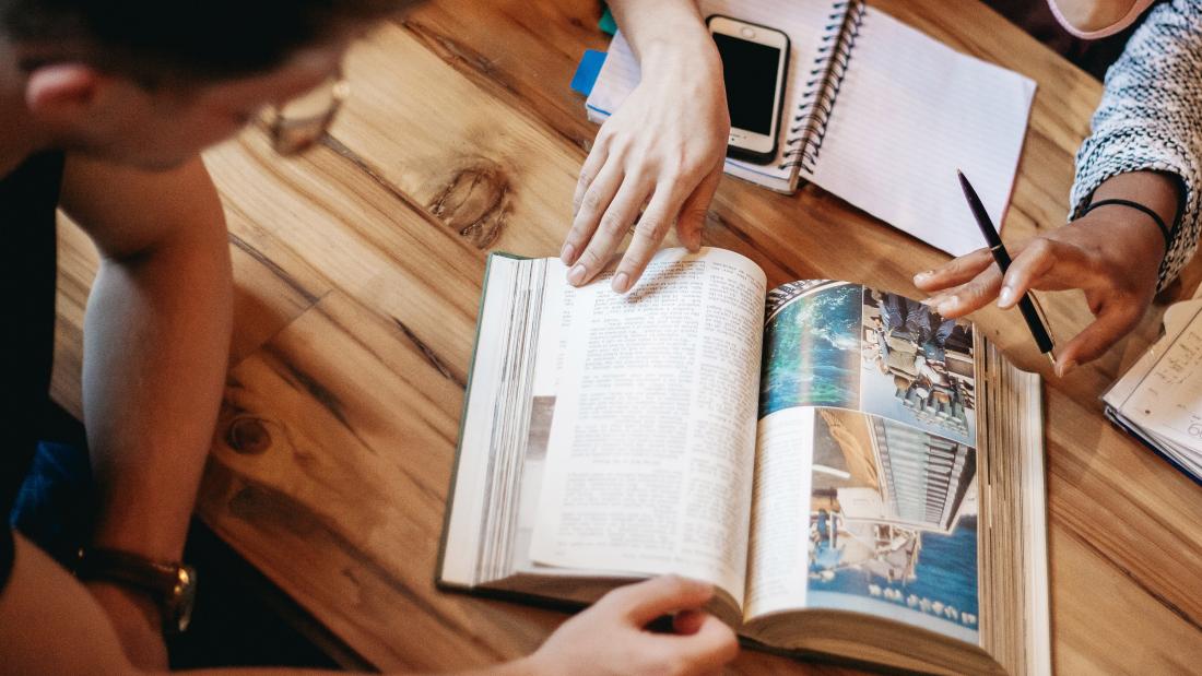 students looking at book