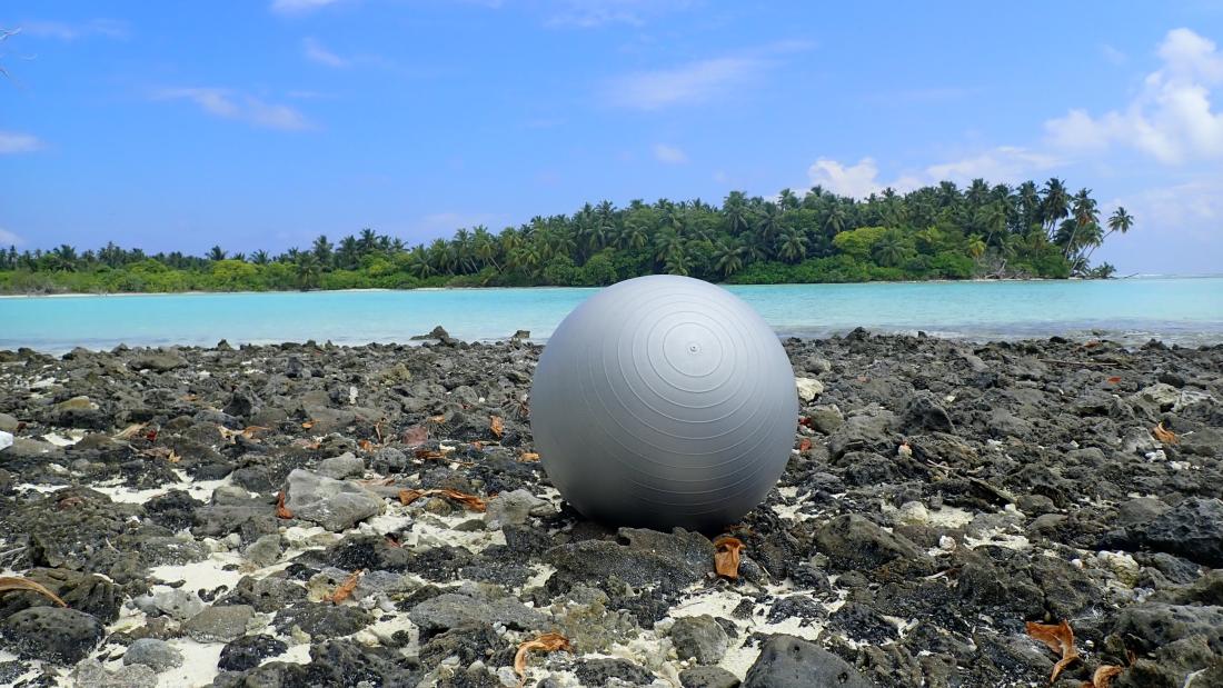 A sports ball lies on the beach on a tropical island