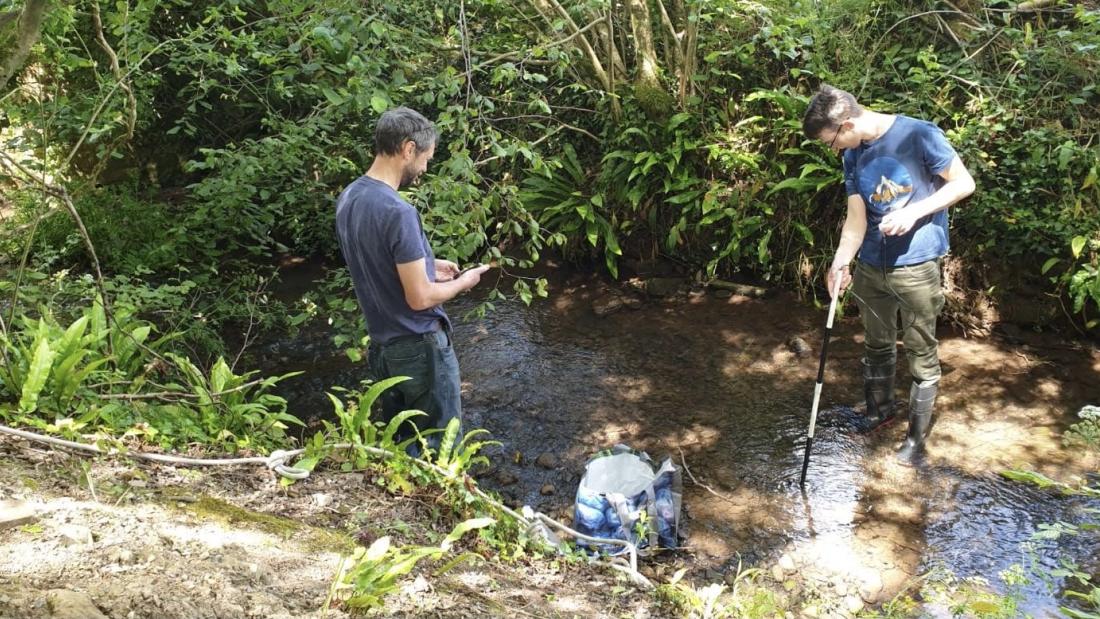 Dan Aberg and Tim Banton collecting water samples in the Whitelake river, while nearby, festival goers had been enjoying Glastonbury Festival back in 2019.