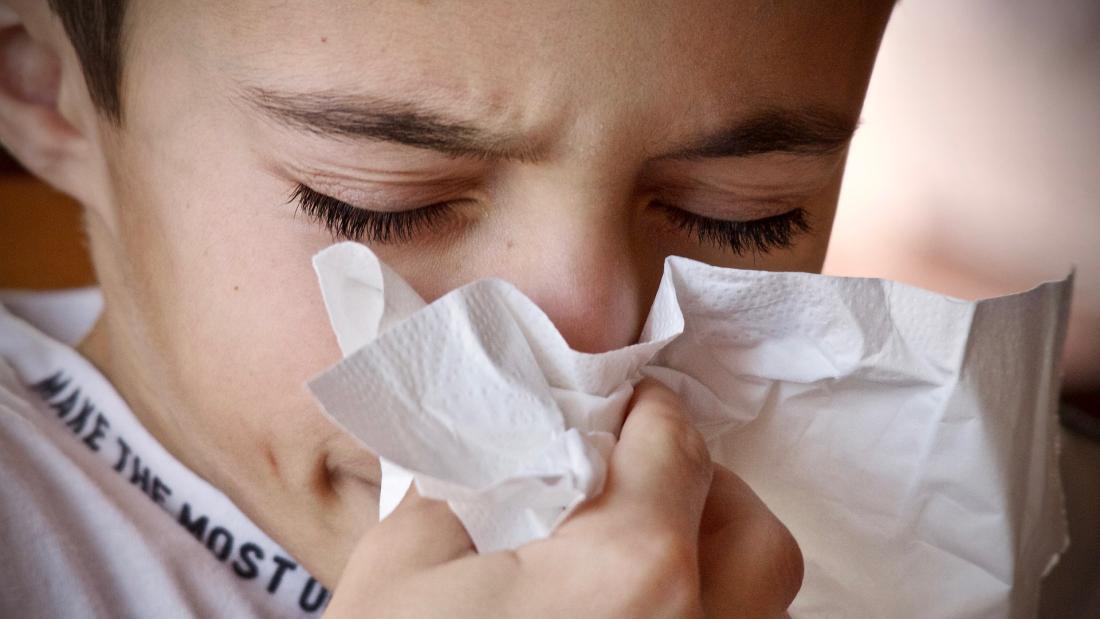 a child blows his nose into a tissue