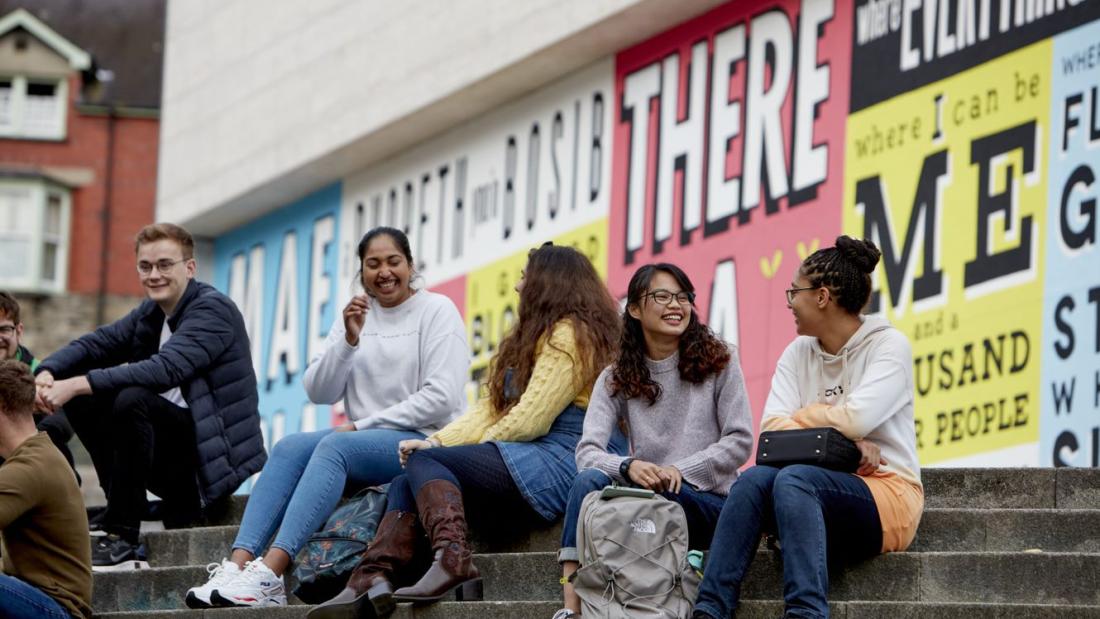 Students sitting on step outside Pontio at Bangor University