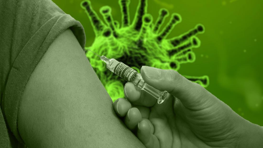 A hand inocculates an arm with vaccine in background is image of coronavirus cell all has a green wash