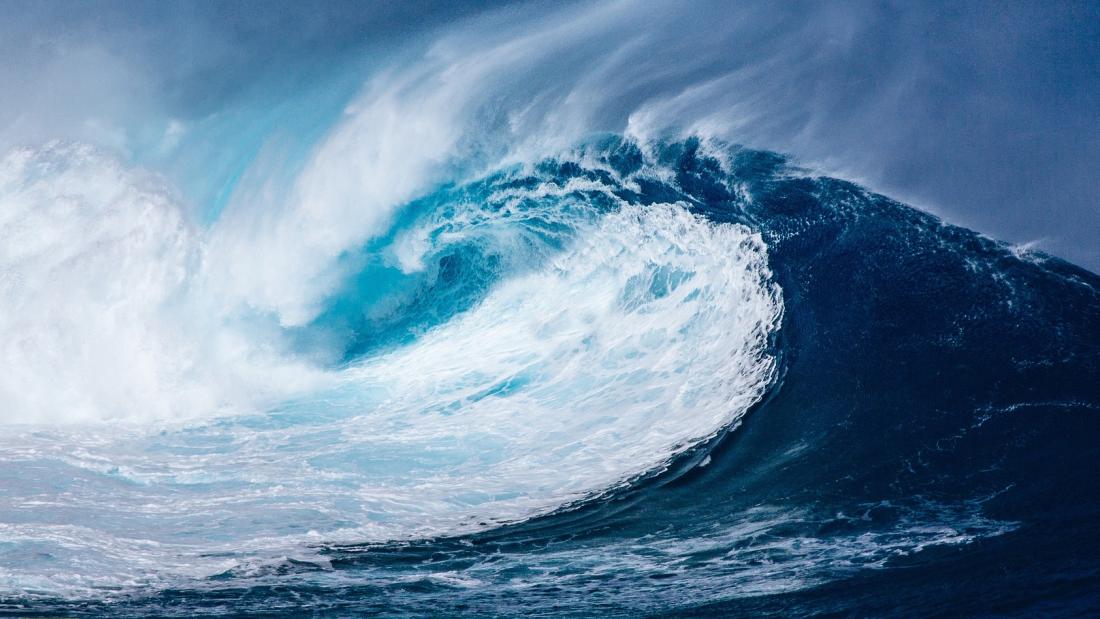 a large blue breaking wave about to topple