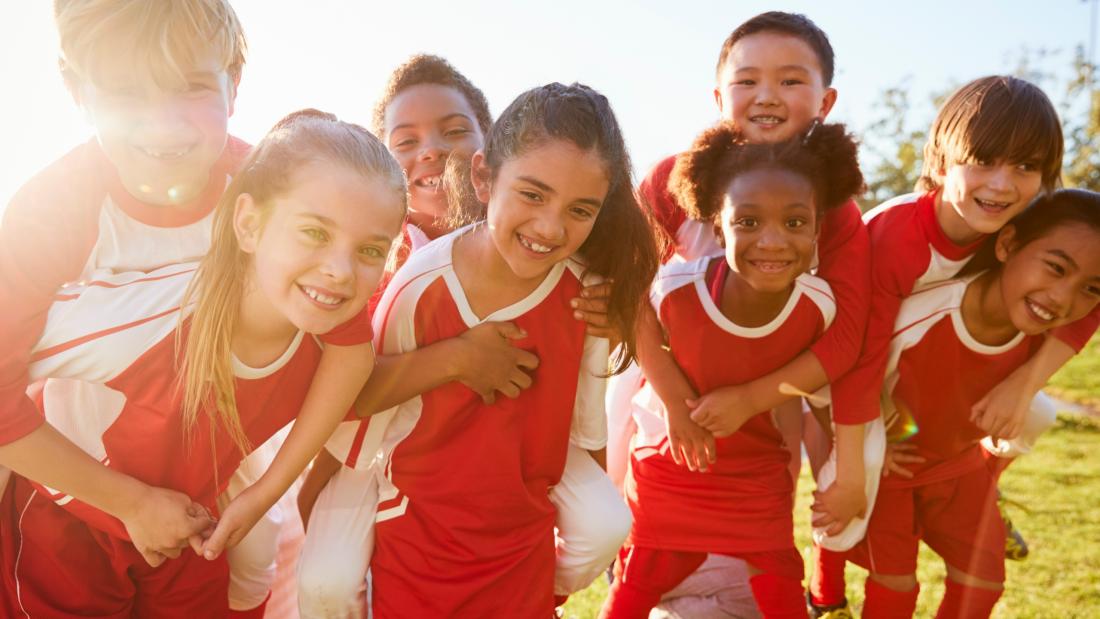 a group of happy children playing football on a sunny day