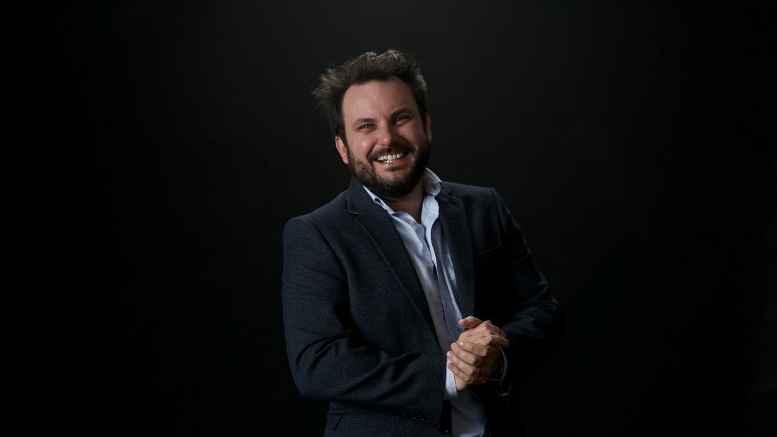 Professor Christian Dunn stands in front of a black background