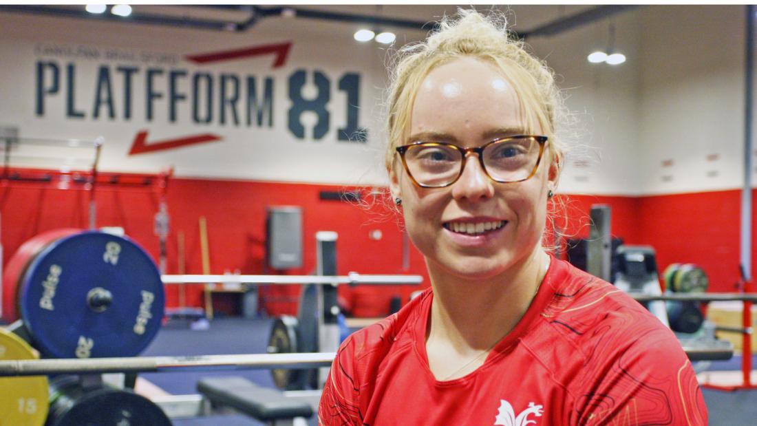 Picture of Catrin Jones wearing a red t-shirt in the weightlifting training facility