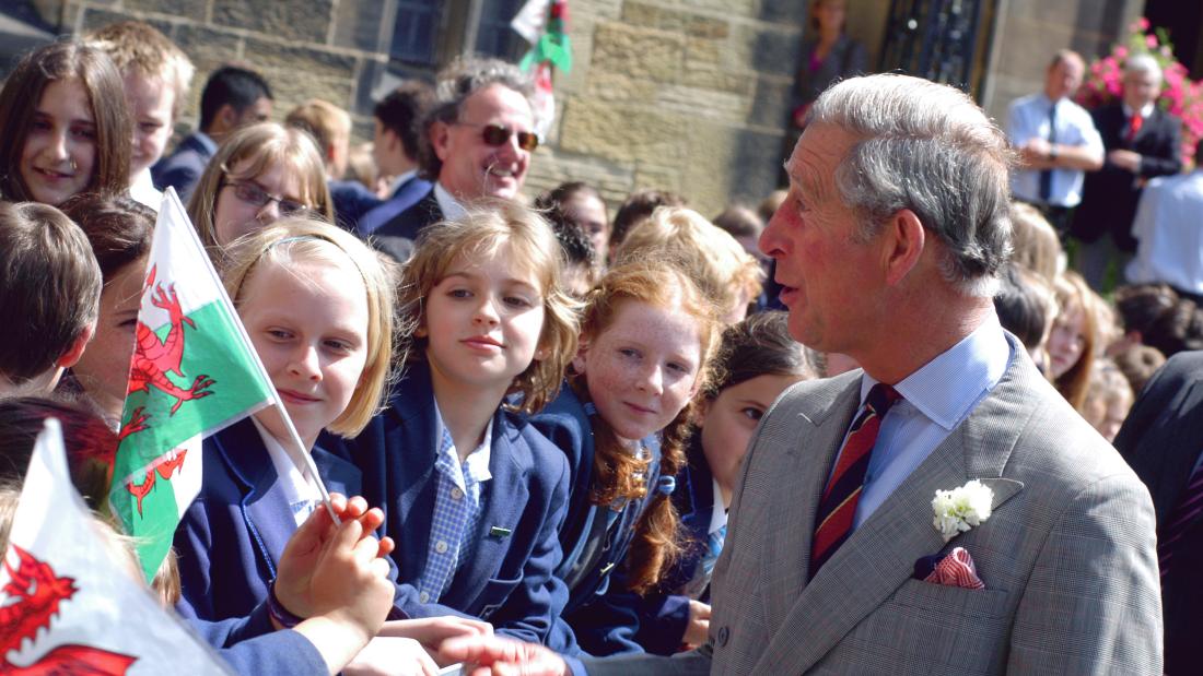  the then Prince Charles speaks with welsh flag waving school children during a visit to Bangor University in 2009