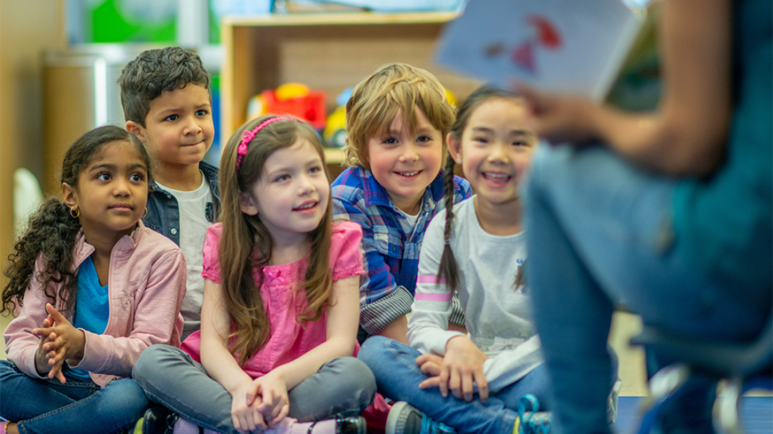 Children sitting in a classroom, learning from the teacher