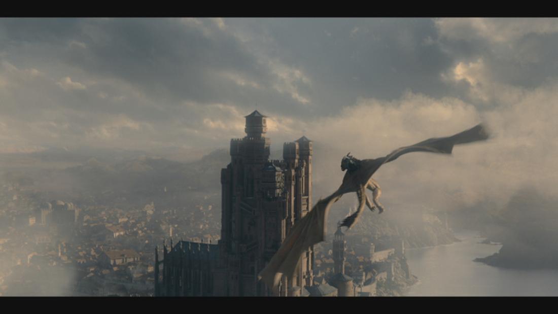 A still from the series showing a flying dragon against a skyline with tall building