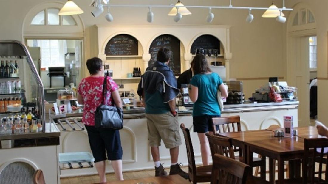 Three people in a queue in a tea room