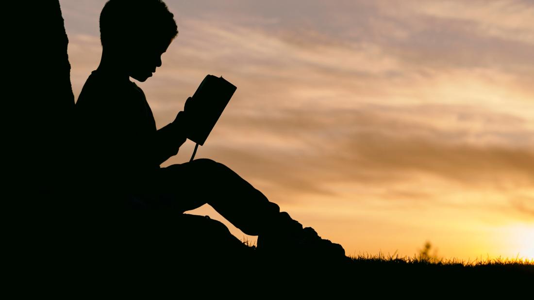 A child reading a book outside