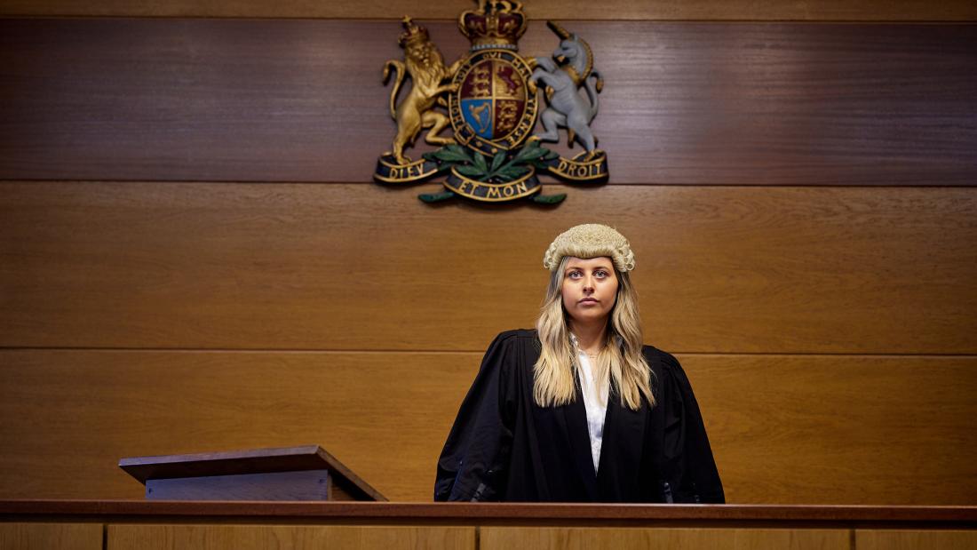 Student looking ahead standing in mock courtroom at Bangor University
