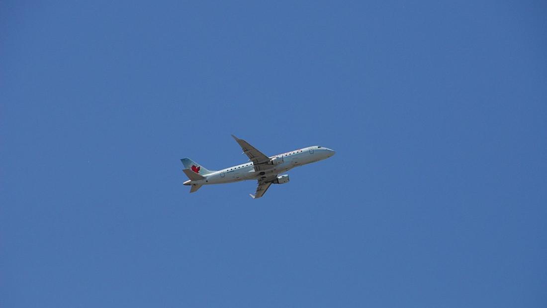 A passenger aeroplane appears quite small against a blue sky