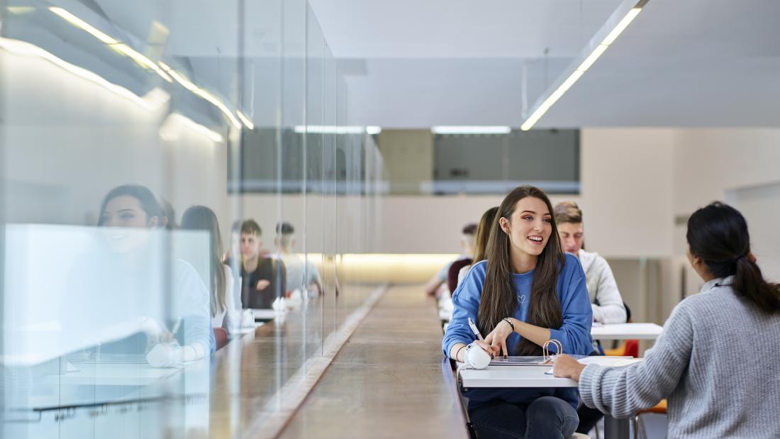 Image of a group of students sitting by a table at the Pontio learning space